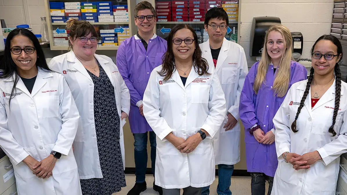 clinical researchers and physicians standing in a group posing for a picture with lab coats on