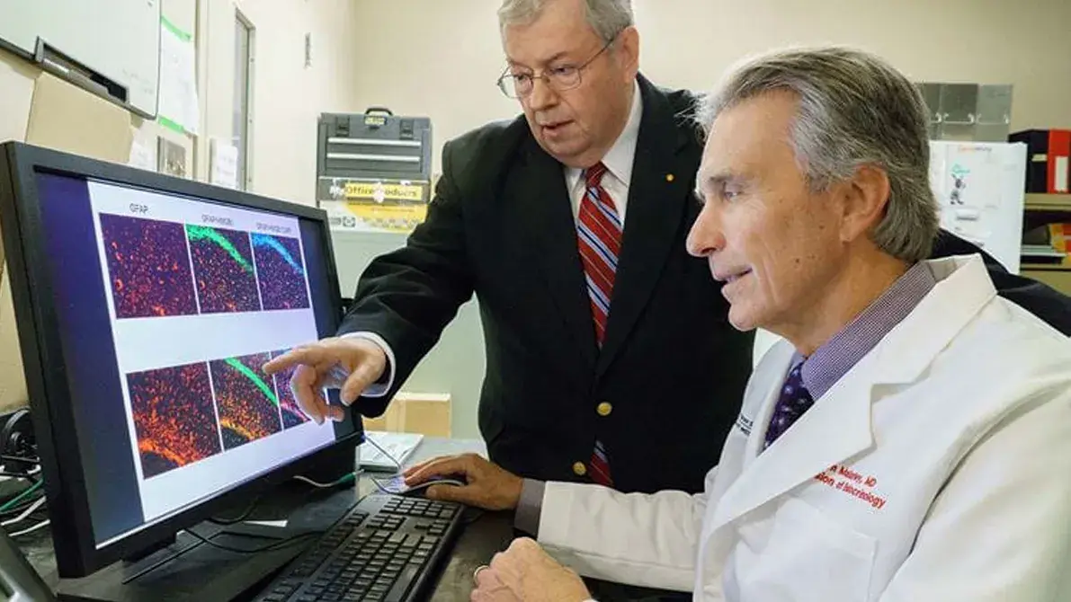 two men examine results on a computer screen