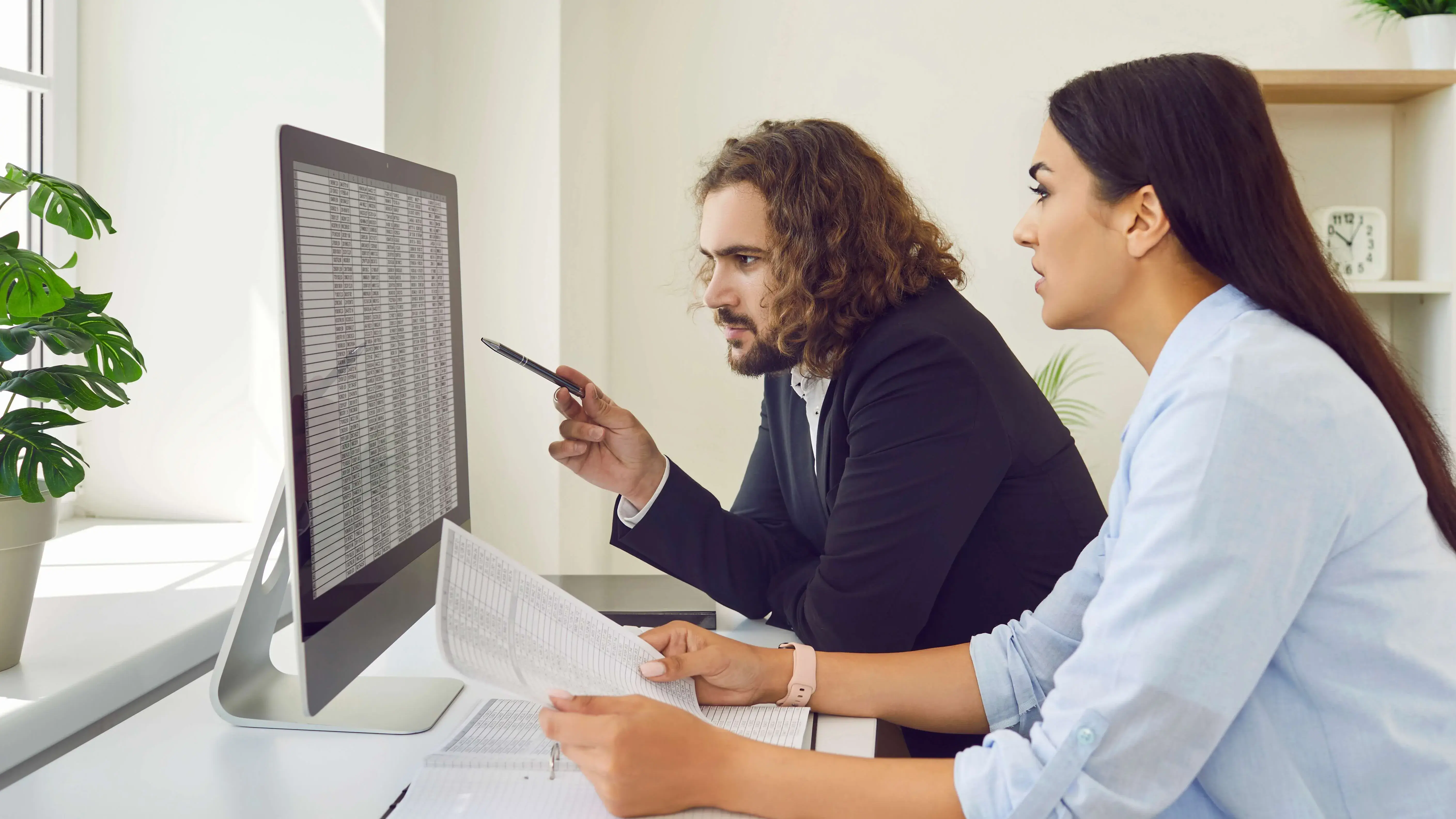 Two coworkers reviewing data on a computer